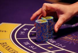 Live dealer holding ball above spinning wheel during active game